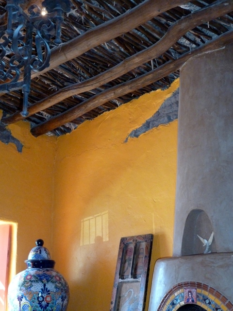 The 1800s adobe peeking through from beneath viga ceiling